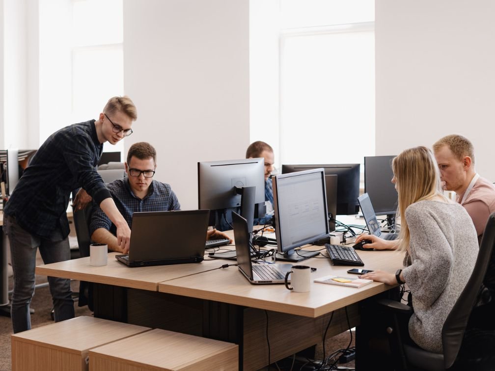 Professional web developers working on modern computers with code on screens, collaborative workspace in a tech office setting.